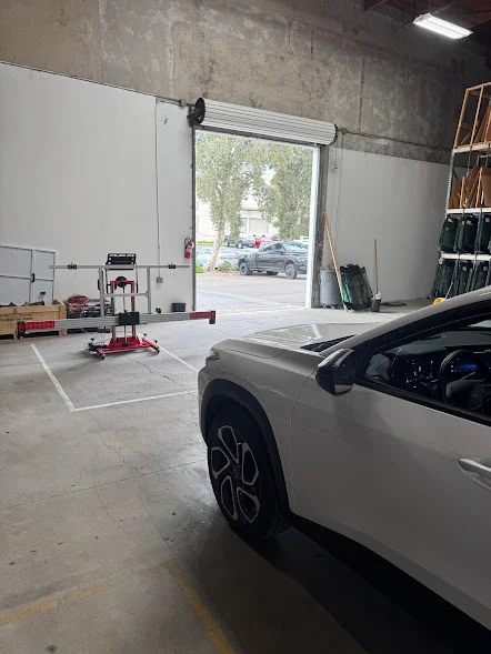SUV in the Majesty Auto Glass shop being prepped for a windshield replacement next to a glass storage rack